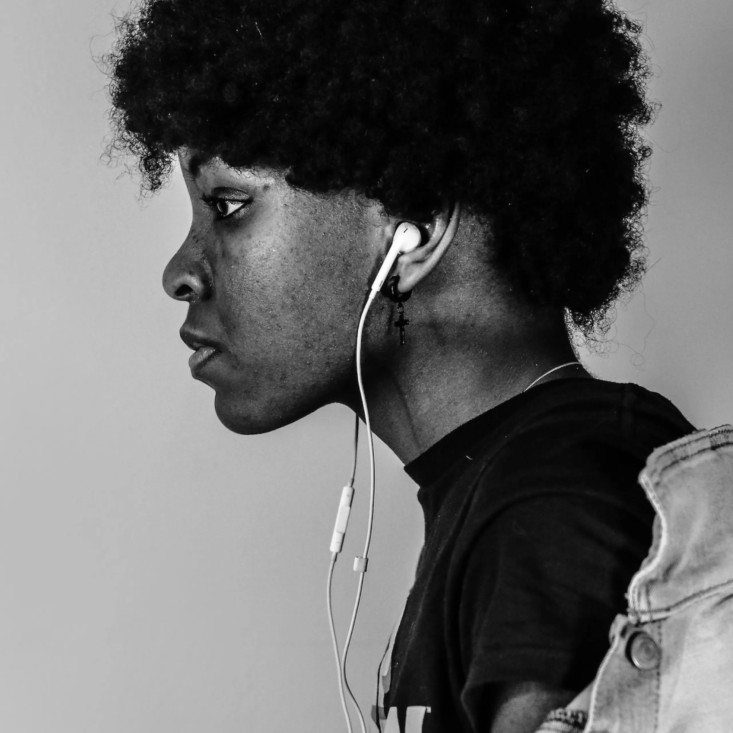 Black and white profile portrait of a person wearing white earphones.