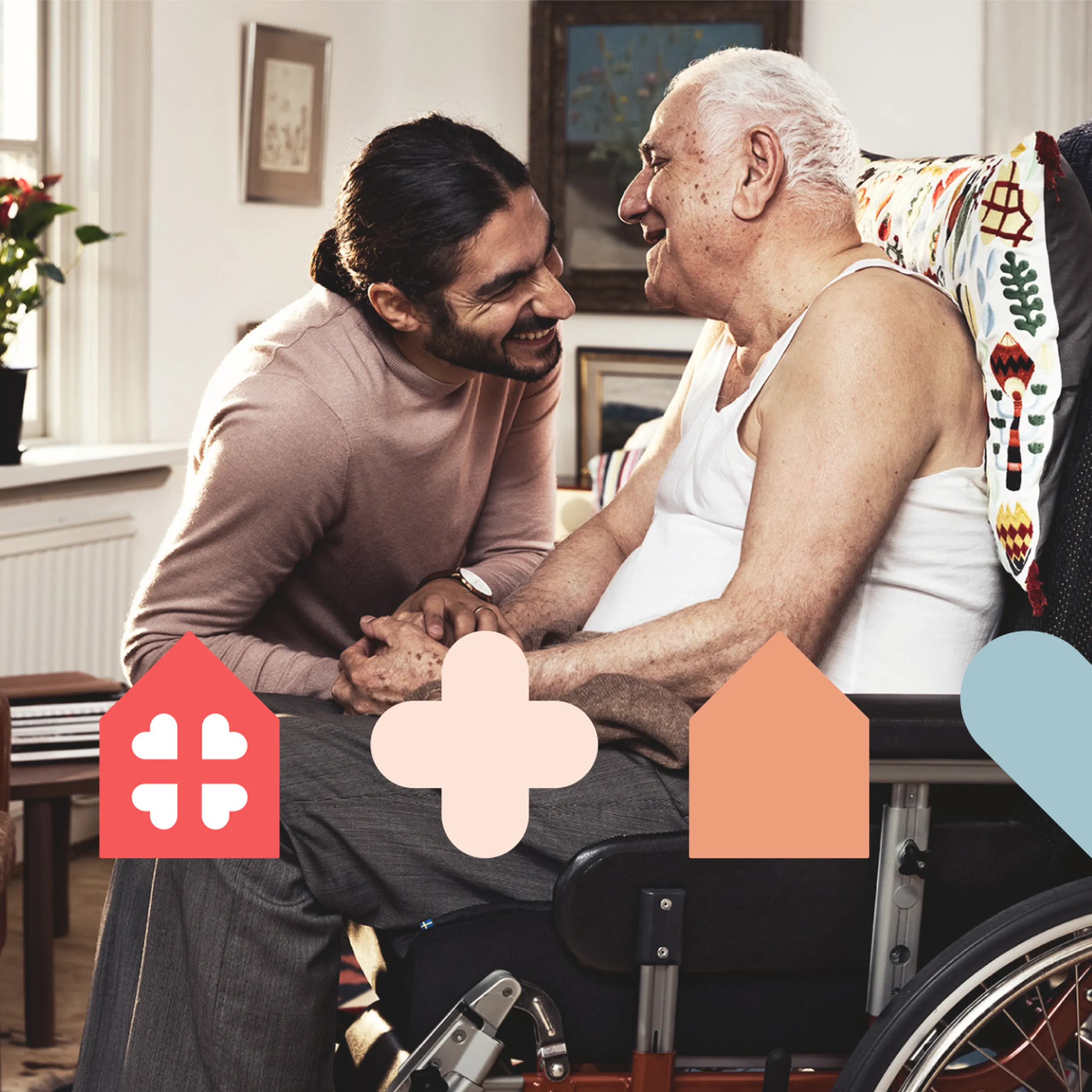 A smiling man leans towards an elderly man in a wheelchair, both sharing a warm moment in a cozy room adorned with colorful décor.